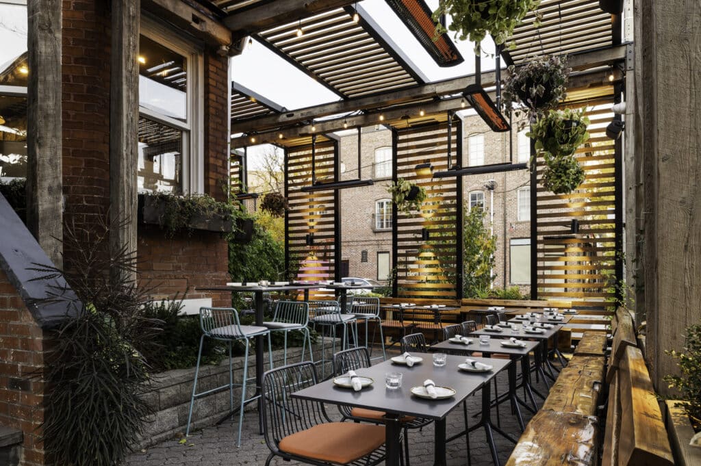 Outdoor restaurant patio with overhead electric heaters and diners seated